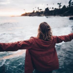 Une personne avec les bras écartés respire devant la mer